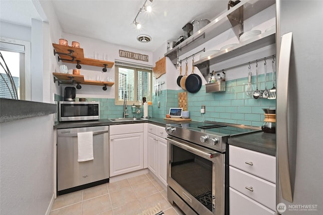 kitchen with a sink, open shelves, dark countertops, and stainless steel appliances