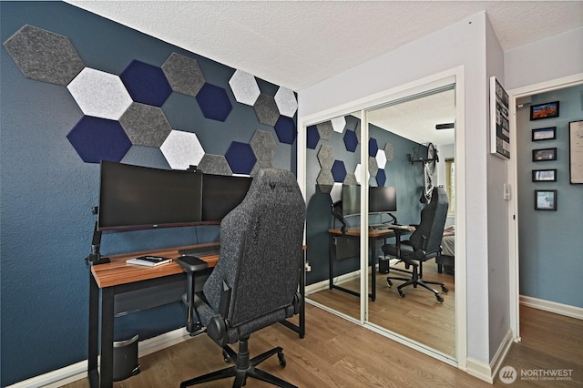 home office with a textured ceiling, baseboards, and wood finished floors