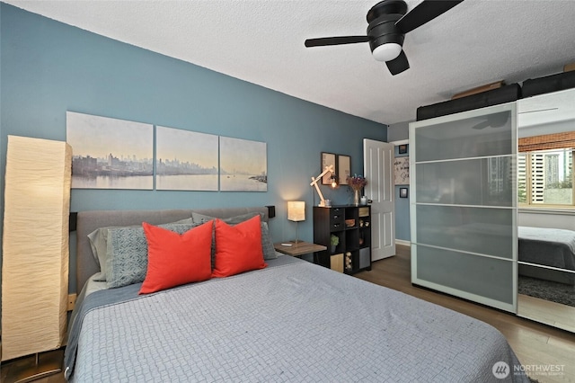 bedroom featuring a textured ceiling, ceiling fan, and wood finished floors