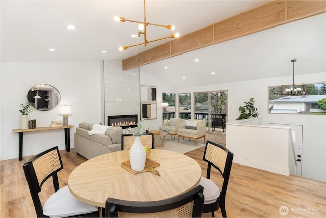 dining area featuring vaulted ceiling with beams, recessed lighting, a fireplace, light wood-type flooring, and an inviting chandelier