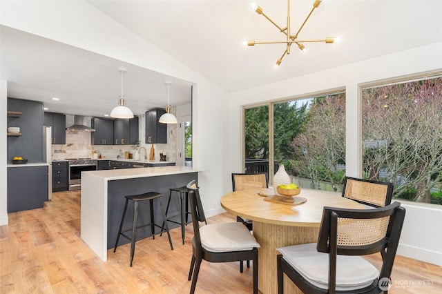 dining area with vaulted ceiling, an inviting chandelier, baseboards, and light wood-style floors