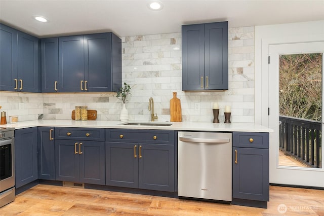 kitchen with light wood-style flooring, appliances with stainless steel finishes, light countertops, and a sink