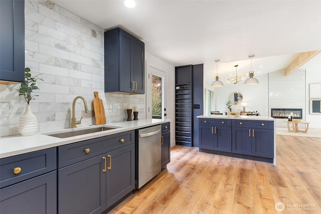 kitchen featuring decorative backsplash, stainless steel dishwasher, light countertops, light wood-style floors, and a sink