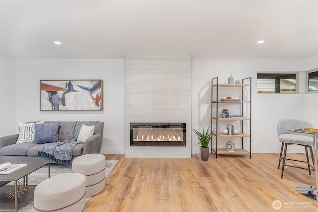 living area with recessed lighting, a fireplace, baseboards, and wood finished floors