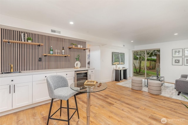 sitting room with wine cooler, recessed lighting, visible vents, light wood-style floors, and baseboards