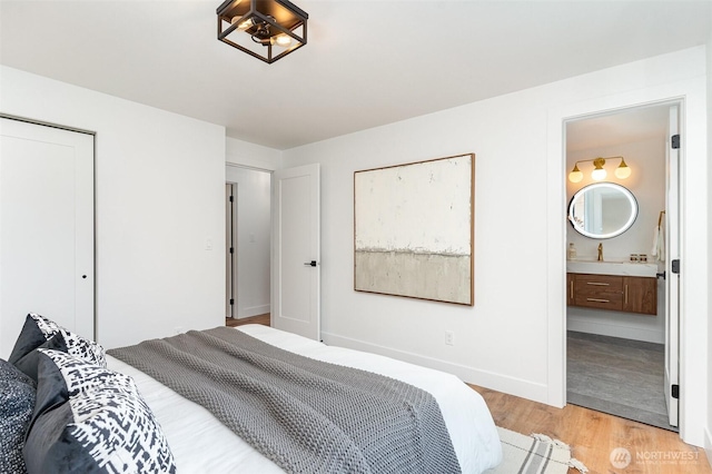 bedroom featuring light wood-style floors, a closet, ensuite bath, and baseboards