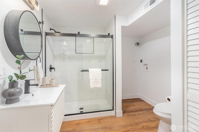 full bath with visible vents, toilet, vanity, a shower stall, and wood finished floors