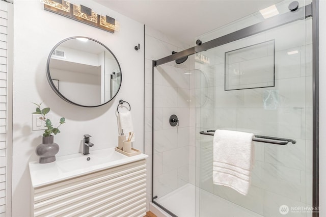 full bathroom featuring visible vents, a shower stall, and vanity