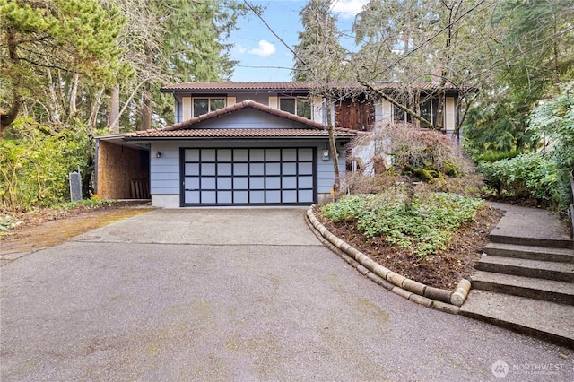 view of front of home featuring driveway, a tile roof, and a garage