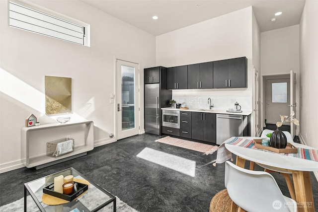 kitchen featuring built in appliances, concrete flooring, dark cabinets, a sink, and backsplash