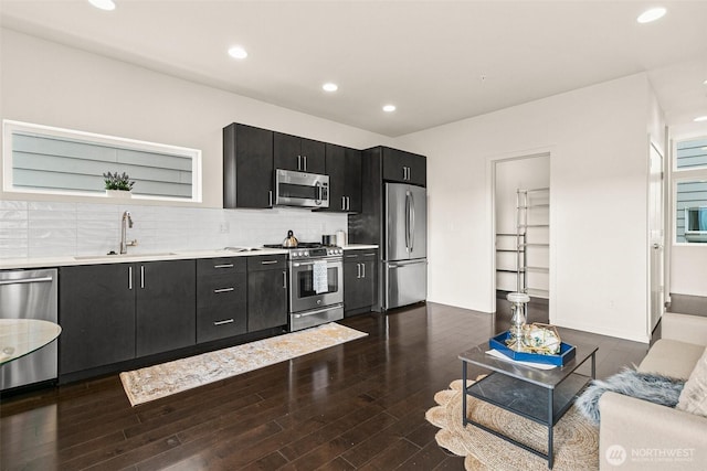 kitchen featuring dark cabinets, a sink, light countertops, appliances with stainless steel finishes, and tasteful backsplash