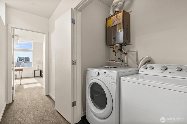 clothes washing area featuring washing machine and dryer, light colored carpet, laundry area, baseboards, and water heater