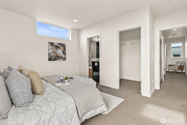 bedroom with a closet, multiple windows, a walk in closet, and carpet flooring