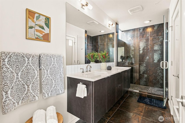 full bathroom featuring a sink, a shower stall, and double vanity