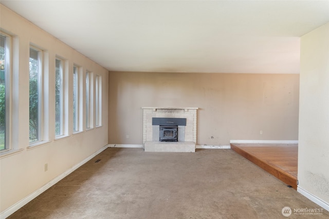 unfurnished living room with visible vents, carpet flooring, a wealth of natural light, and baseboards