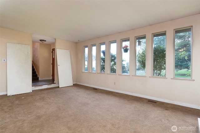 spare room featuring baseboards, visible vents, stairway, and carpet flooring