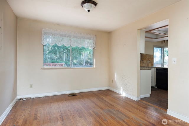 unfurnished room with wood finished floors, visible vents, and a healthy amount of sunlight