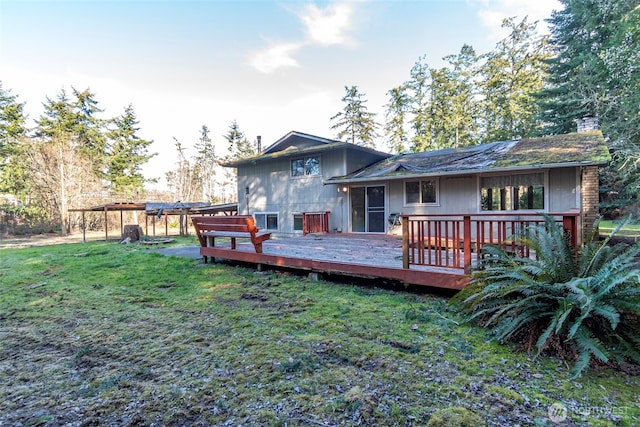 rear view of property with a yard, a chimney, and a wooden deck