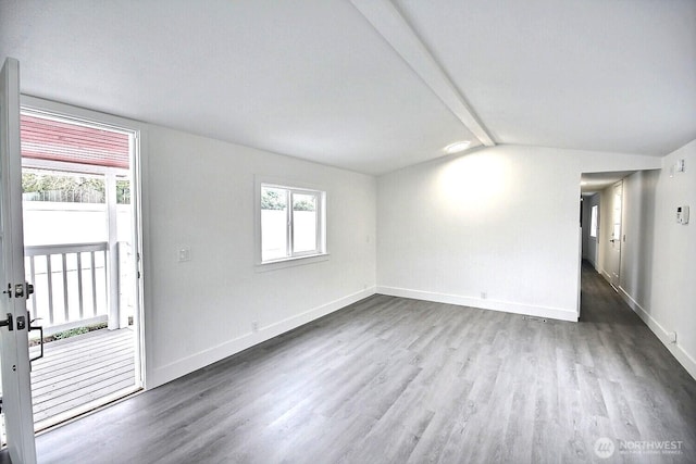 spare room featuring plenty of natural light, vaulted ceiling with beams, baseboards, and wood finished floors