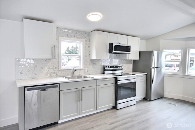 kitchen with stainless steel appliances, tasteful backsplash, visible vents, light wood-style floors, and a sink