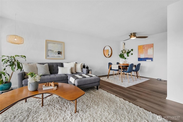 living area with wood finished floors, a ceiling fan, and baseboards