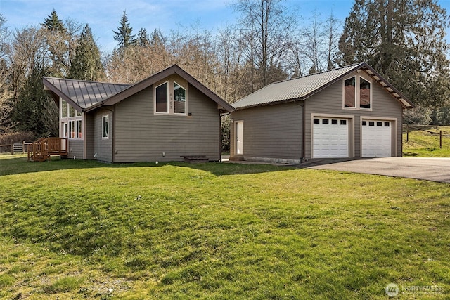 view of property exterior with a garage, an outbuilding, metal roof, and a yard