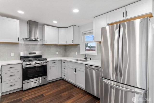 kitchen featuring dark wood-style flooring, stainless steel appliances, tasteful backsplash, a sink, and wall chimney range hood