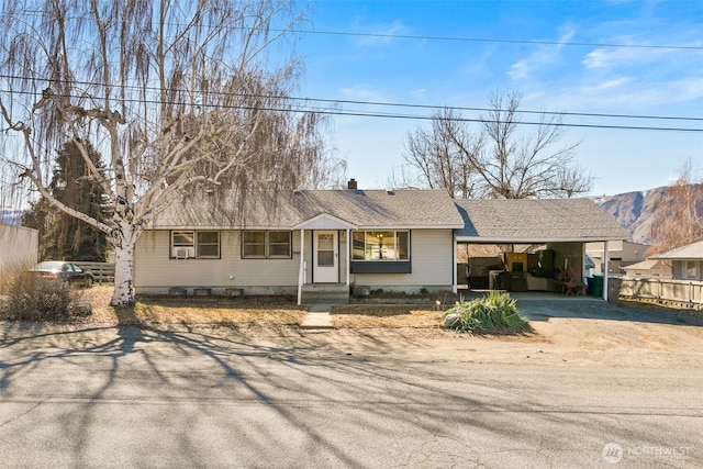 ranch-style house featuring a carport, roof with shingles, fence, and a chimney