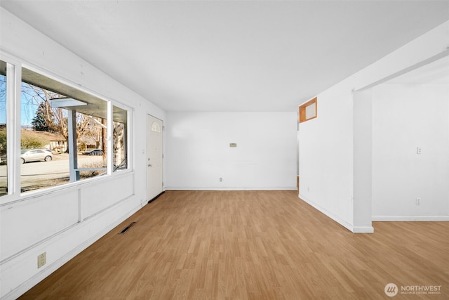 spare room featuring visible vents, light wood-style flooring, and baseboards