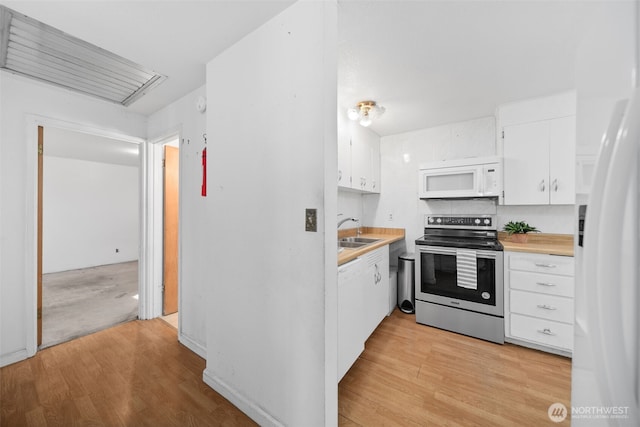 kitchen featuring white cabinets, white appliances, light countertops, and a sink