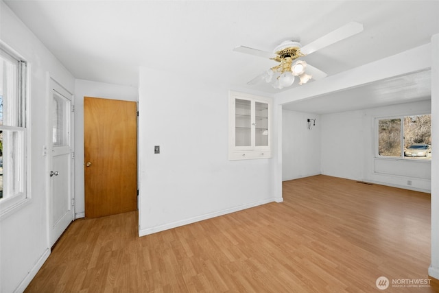 spare room featuring baseboards, ceiling fan, visible vents, and light wood-style floors