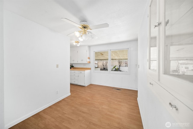 unfurnished room featuring visible vents, light wood finished floors, a ceiling fan, and baseboards