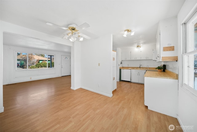 kitchen featuring light countertops, light wood-style floors, white cabinetry, dishwasher, and baseboards