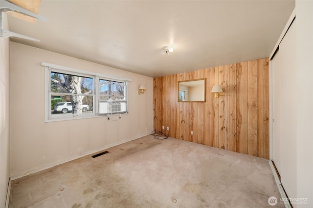 unfurnished room featuring carpet, cooling unit, visible vents, and wooden walls