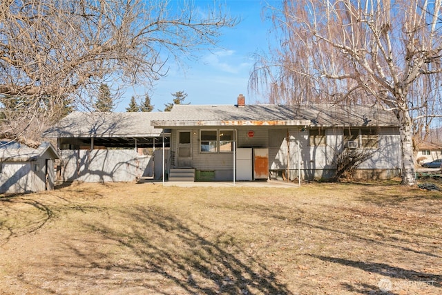 rear view of property with entry steps, a lawn, and a chimney