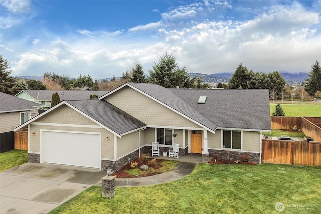 view of front facade featuring stone siding, concrete driveway, a front yard, and fence