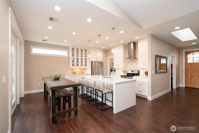 kitchen with a breakfast bar, a sink, visible vents, appliances with stainless steel finishes, and wall chimney exhaust hood