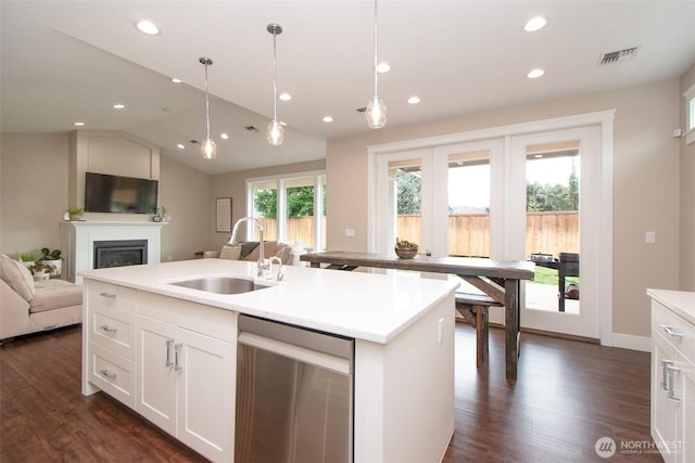 kitchen featuring visible vents, dishwasher, open floor plan, vaulted ceiling, and a sink