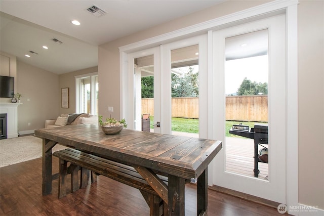 dining room with dark wood-style floors, recessed lighting, visible vents, and a glass covered fireplace