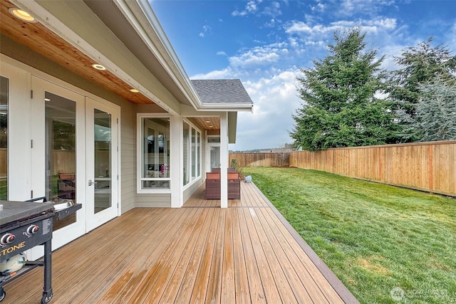 deck featuring fence private yard, french doors, and a lawn