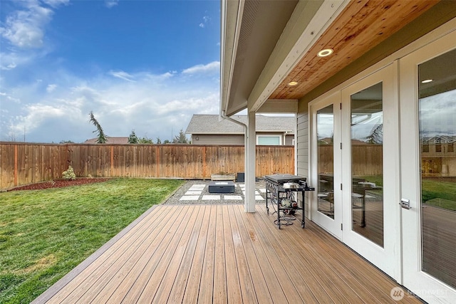 wooden deck featuring a yard, a fenced backyard, and french doors