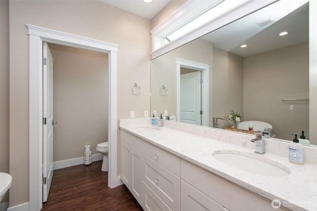 bathroom featuring toilet, recessed lighting, a sink, and wood finished floors