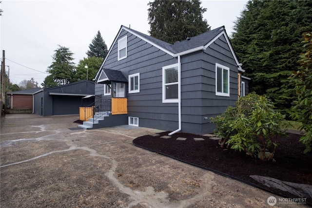 exterior space featuring an outbuilding and roof with shingles