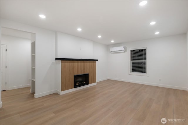 unfurnished living room featuring recessed lighting, light wood-style floors, a fireplace, and a wall mounted AC