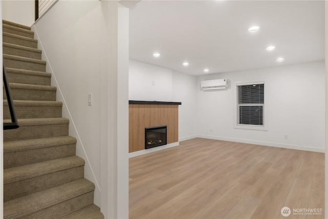 finished below grade area with a fireplace, light wood-style flooring, recessed lighting, and a wall mounted AC