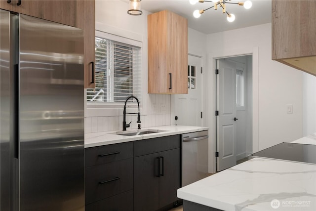 kitchen featuring a sink, stainless steel appliances, light stone counters, and modern cabinets