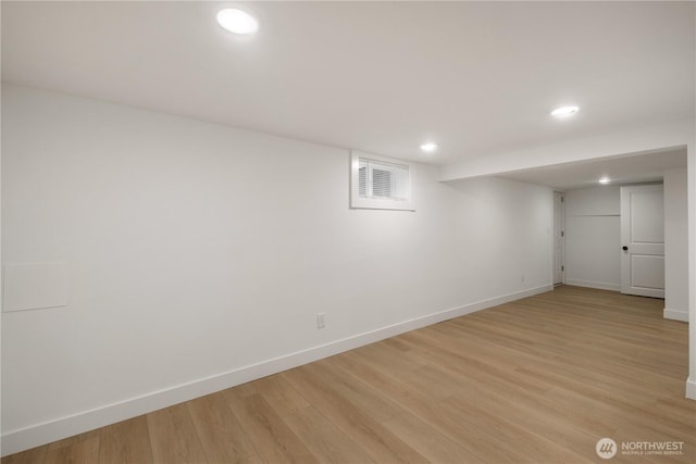 finished basement with light wood-type flooring, visible vents, and baseboards