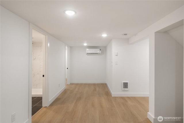 interior space with light wood finished floors, recessed lighting, a wall mounted air conditioner, and baseboards