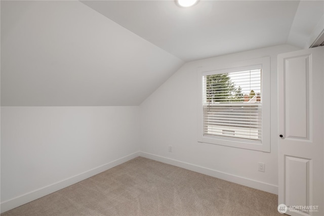 additional living space featuring baseboards, light carpet, and vaulted ceiling