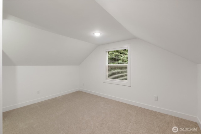 additional living space with baseboards, light carpet, and lofted ceiling